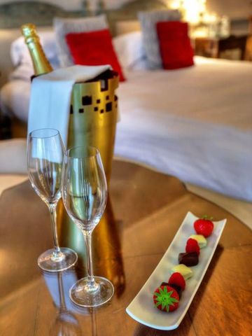 Champagner und Pralinen auf edlem Tisch im Schlafzimmer.