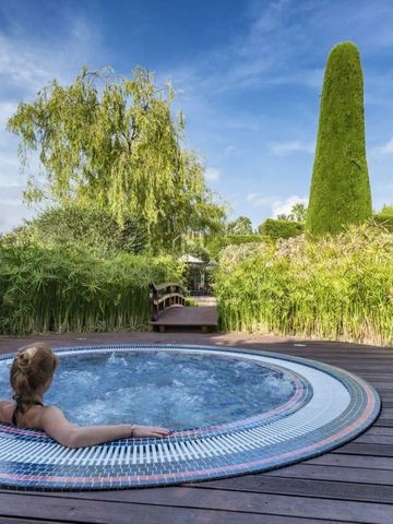 Person im entspannenden Whirlpool mit üppigem Garten im Hintergrund