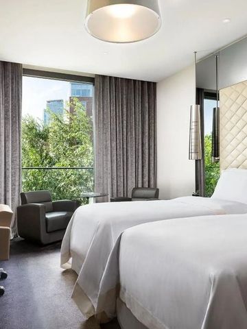 Modernes Doppelzimmer mit großen Fenstern und Blick ins Grüne