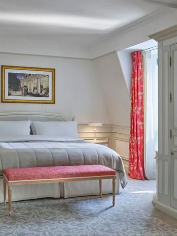 Helles Hotelzimmer mit roten Vorhängen und edlem Mobiliar.