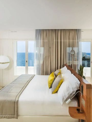 Schlafzimmer mit heller Einrichtung und Panoramafenstern zum Meer