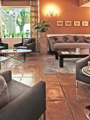 Eleganter Lounge-Bereich mit stilvollen Sesseln und Blick in den grünen Garten.