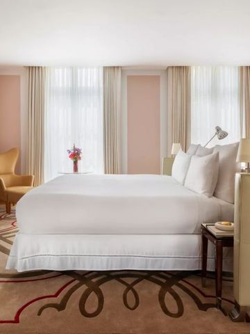 Elegantes Hotelzimmer mit großem Bett, Sesseln und dezentem Dekor.