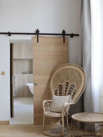 Geräumiges Zimmer mit Rattanstuhl und Schiebetür aus Holz in natürlichem Licht