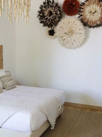 Helles Schlafzimmer mit dekorativer Wandkunst über dem Bett und natürlicher Einrichtung