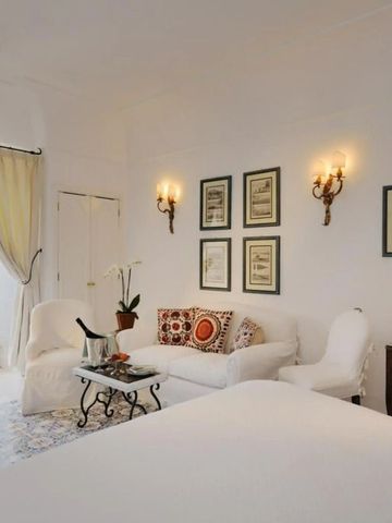 Helles Hotelzimmer mit gemütlicher Sitzecke und Meerblick.