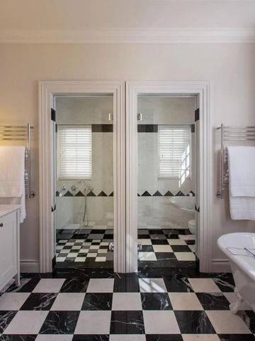 Großes Badezimmer mit schwarz-weißen Fliesen und doppeltem Waschbecken.