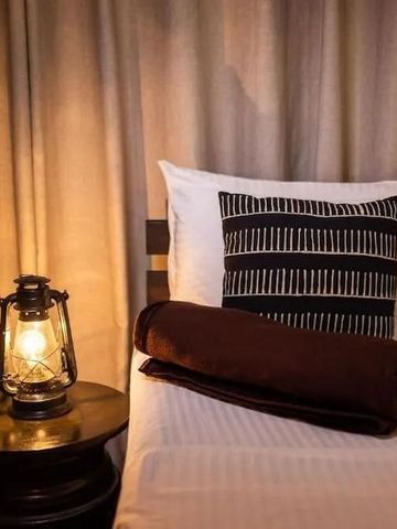 Detailaufnahme von Bett mit stilvoller Lampe und dekorativem Kissen