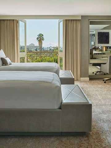 Luxuriöses Doppelzimmer mit großen Fenstern und Blick auf die Stadt mit Palmen