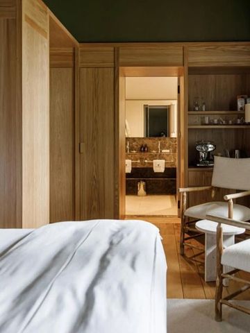 Helles Hotelzimmer mit gemütlicher Sitzecke und Blick auf das luxuriöse Badezimmer