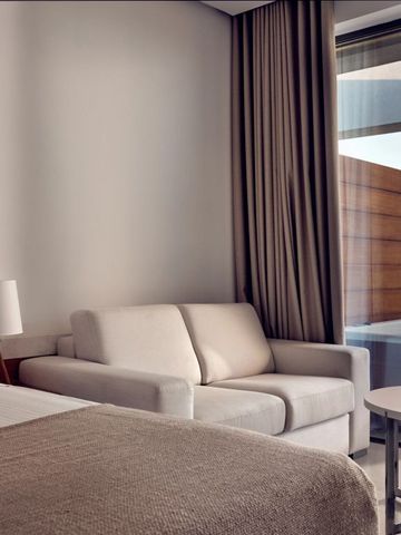 Zimmer mit Sofa, Meerblick und moderner Einrichtung in neutralen Farben.