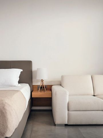 Gemütliches Hotelzimmer mit Bett und beiger Couch