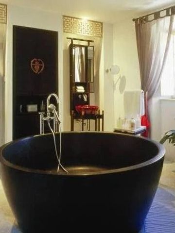 Luxuriöses Badezimmer mit freistehender schwarzer Badewanne und großen Spiegeln