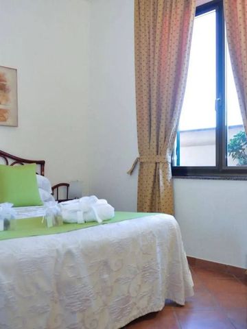 Helles Hotelzimmer mit Doppelbett und großen Fenstern, frische grüne Akzente