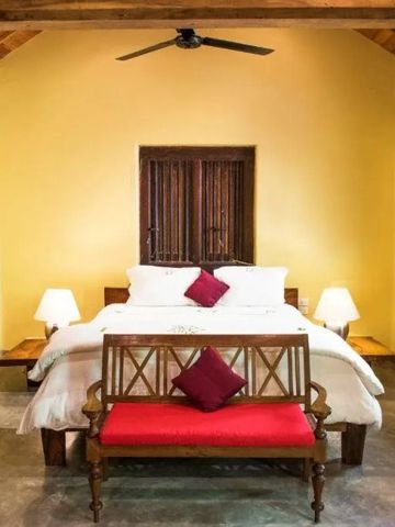 Schlafzimmer mit Holzbalkendecke und weißer Bettwäsche auf einem großen Bett