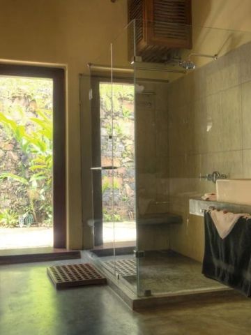 Modernes Badezimmer mit gläserner Dusche und Blick auf einen grünen Garten