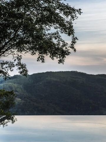 Infinity-Pool mit Blick auf bewaldete Hügel bei Sonnenaufgang