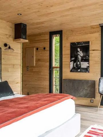 Modernes Zimmer mit Holzwänden, Doppelbett, großem Fenster und Waldblick.