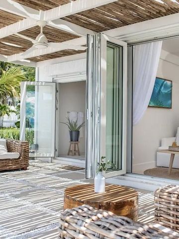 Terrasse mit Rattansesseln und Zugang zu einem eleganten Wohnzimmer