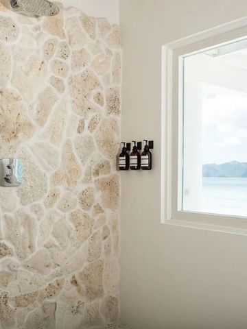 Steinwand in Dusche mit Meerblick durch Fenster