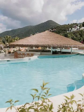 Großer Pool mit Strohdach-Pavillon und Hügel im Hintergrund
