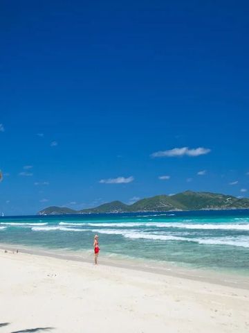 Weißer Sandstrand mit sanftem Wellengang und klarem blauem Himmel