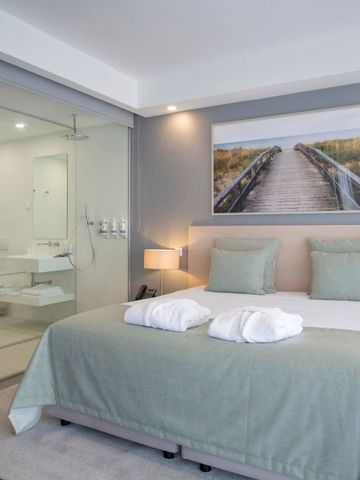 Geräumiges Hotelzimmer mit großem Bett und gläsernem Badezimmer.