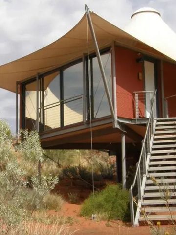 Außenansicht einer modernen Zelt-Suite auf Stelzen mit großem Fenster.