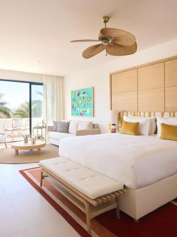 Lichtdurchflutetes Zimmer mit großem Bett und Balkon mit Meerblick