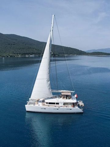 Segelyacht auf klarem blauem Wasser mit Berglandschaft im Hintergrund.