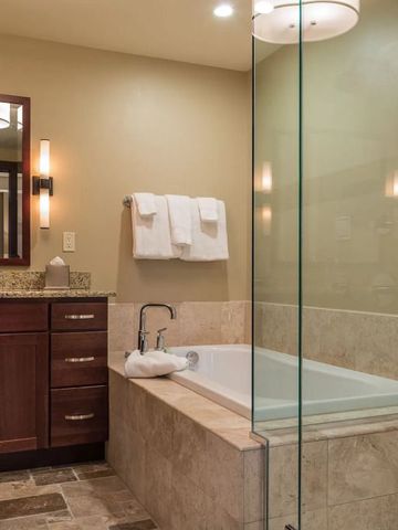 Elegantes Badezimmer mit Glasdusche und stilvollem Waschbereich im Lumiere by Dunton Hotel