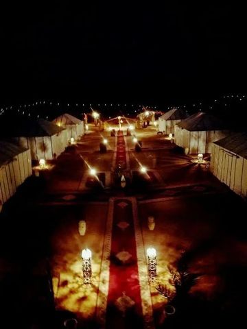 Beleuchtetes Zeltlager bei Nacht mit rotem Teppich