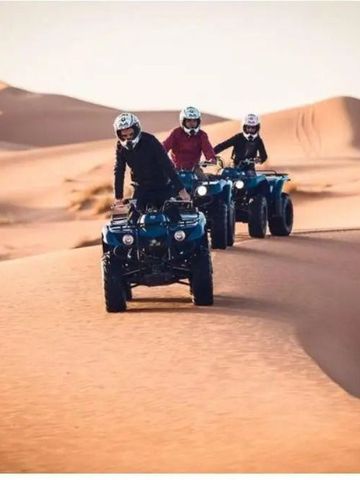 Drei Menschen fahren mit Quads durch die Wüste