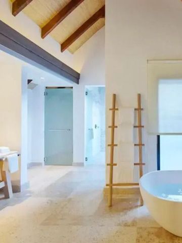 Geräumiges Badezimmer mit freistehender Badewanne und Dachbalken