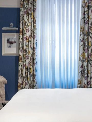 Helles Hotelzimmer mit blauer Wand und floralem Vorhangdekor