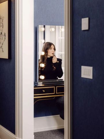 Frau schminkt sich an einem eleganten Schminktisch mit Beleuchtung im Hotelzimmer