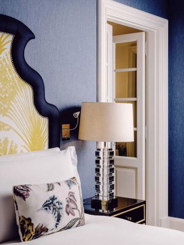 Nachtischlampe und dekoratives Kopfteil an einem gemütlichen Hotelbett