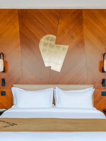 Luxuriöses Hotelzimmer mit Holzwandverkleidung und Kunstwerk über dem Bett