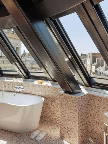 Badewanne neben großem Fenster mit Blick auf Pariser Dächer
