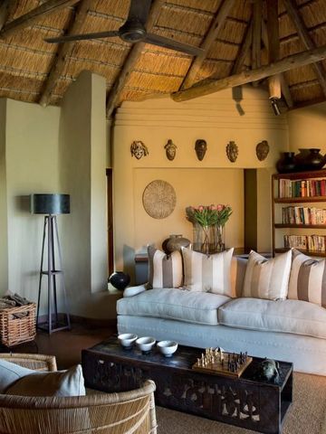 Gemütliche Lounge mit Bücherregal, Kamin und Sofas in der Madikwe Safari Lodge.