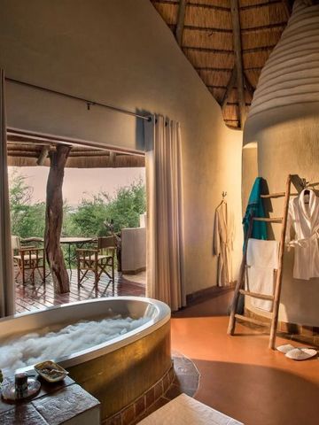 Luxuriöses Badezimmer mit Badewanne und Ausblick auf Terrasse in Safari Lodge.