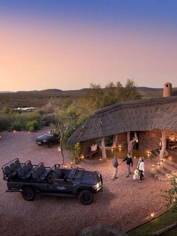 Abendstimmung vor der Madikwe Safari Lodge mit Safari-Fahrzeug und Gästen.
