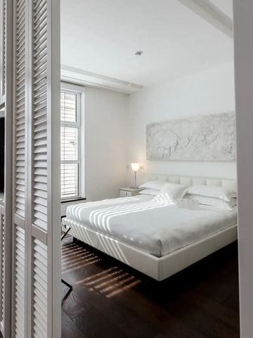 Modernes Hotelzimmer mit weißem Doppelbett und stilvoller Einrichtung