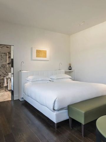 Komfortables Zimmer mit Doppelbett, grüner Sitzbank und Badblick