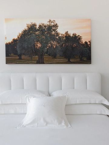 Elegantes Schlafzimmer mit weißem Kopfteil vor Kunstwerk