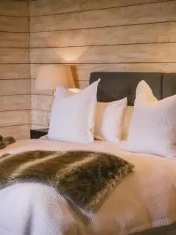 Elegantes Schlafzimmer mit Holztäfelung und kuscheligen Kissen