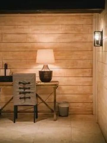 Gemütlicher Holztisch mit Lampe an einer holzgetäfelten Wand