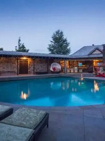 Hotelpool bei Dämmerung mit Liegestühlen und Steinmauer