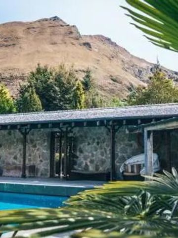 Außenansicht des Pools mit steinverkleideten Gebäuden und Berg im Hintergrund