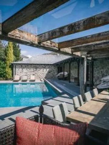 Pool mit Liegestühlen und überdachtem Essbereich unter Holzpaneelen